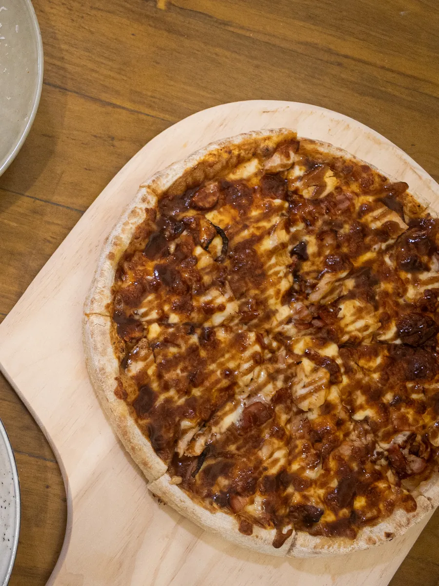 A barbecue meat pizza on a wooden board