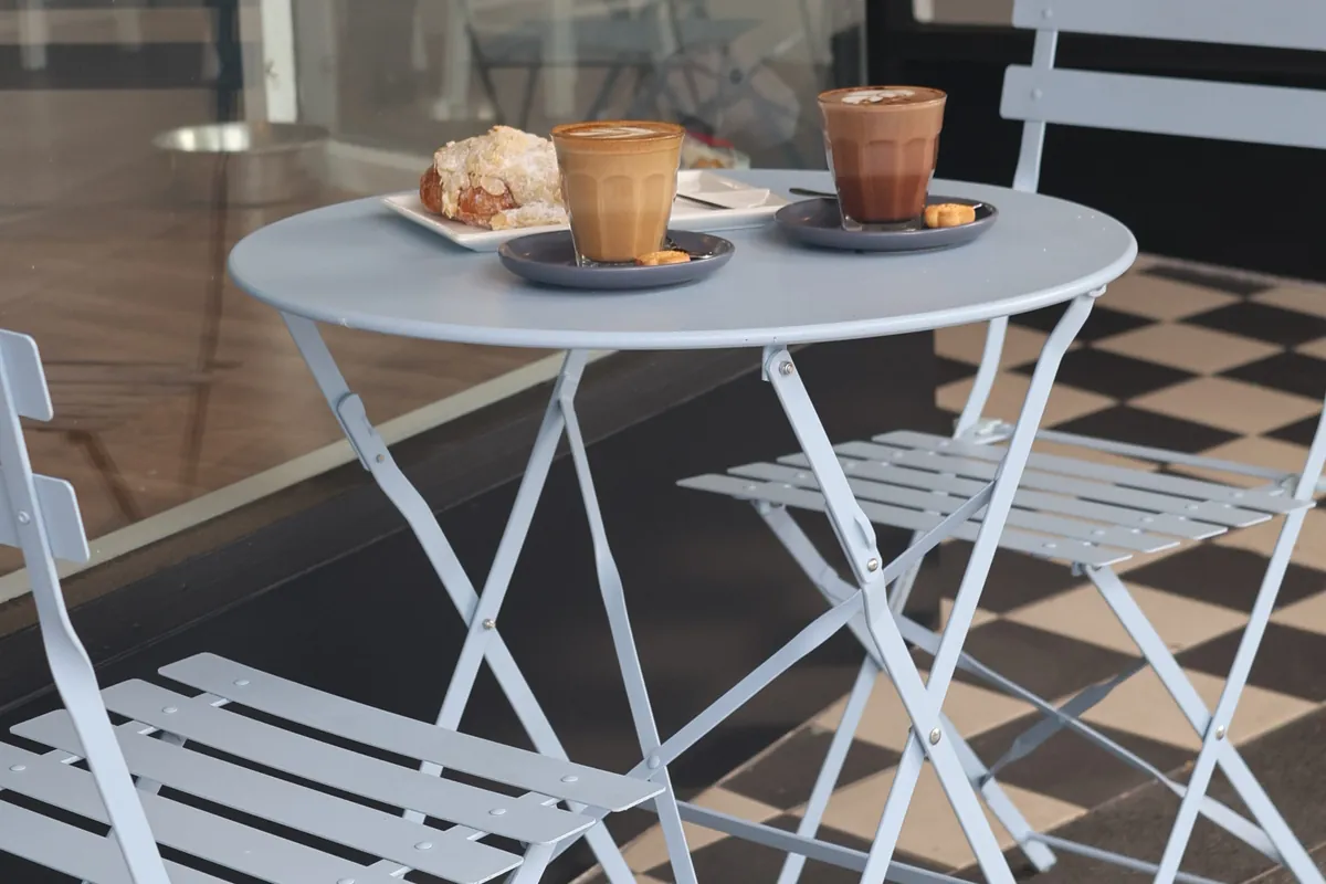 Two coffees and a croissant on a table outside the front window