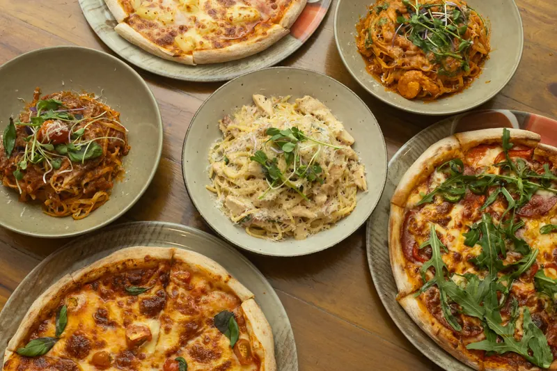 Pasta and pizza dishes spread across a table