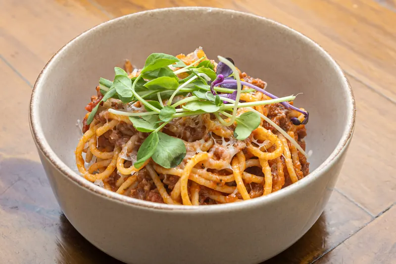 A bowl of spaghetti in tomato sauce with micro herbs