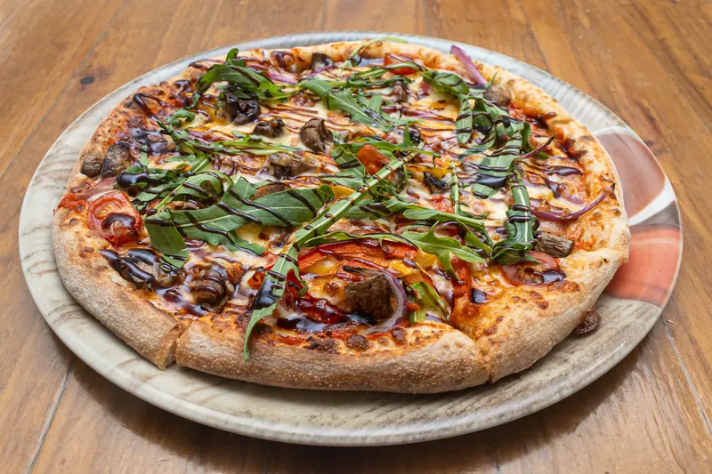 Pizza with capsicum, onion, rocket and balsamic glaze