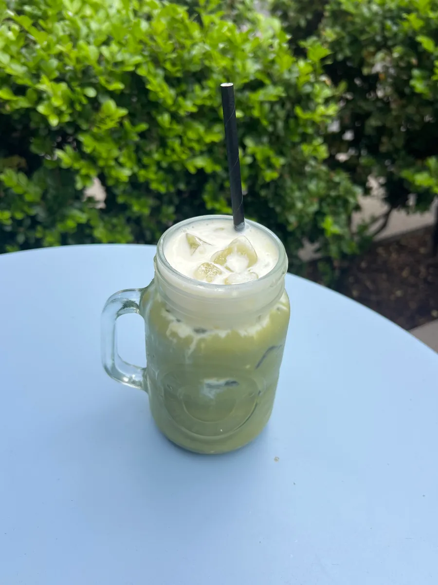 An iced matcha latte in a glass jar on an outdoor table
