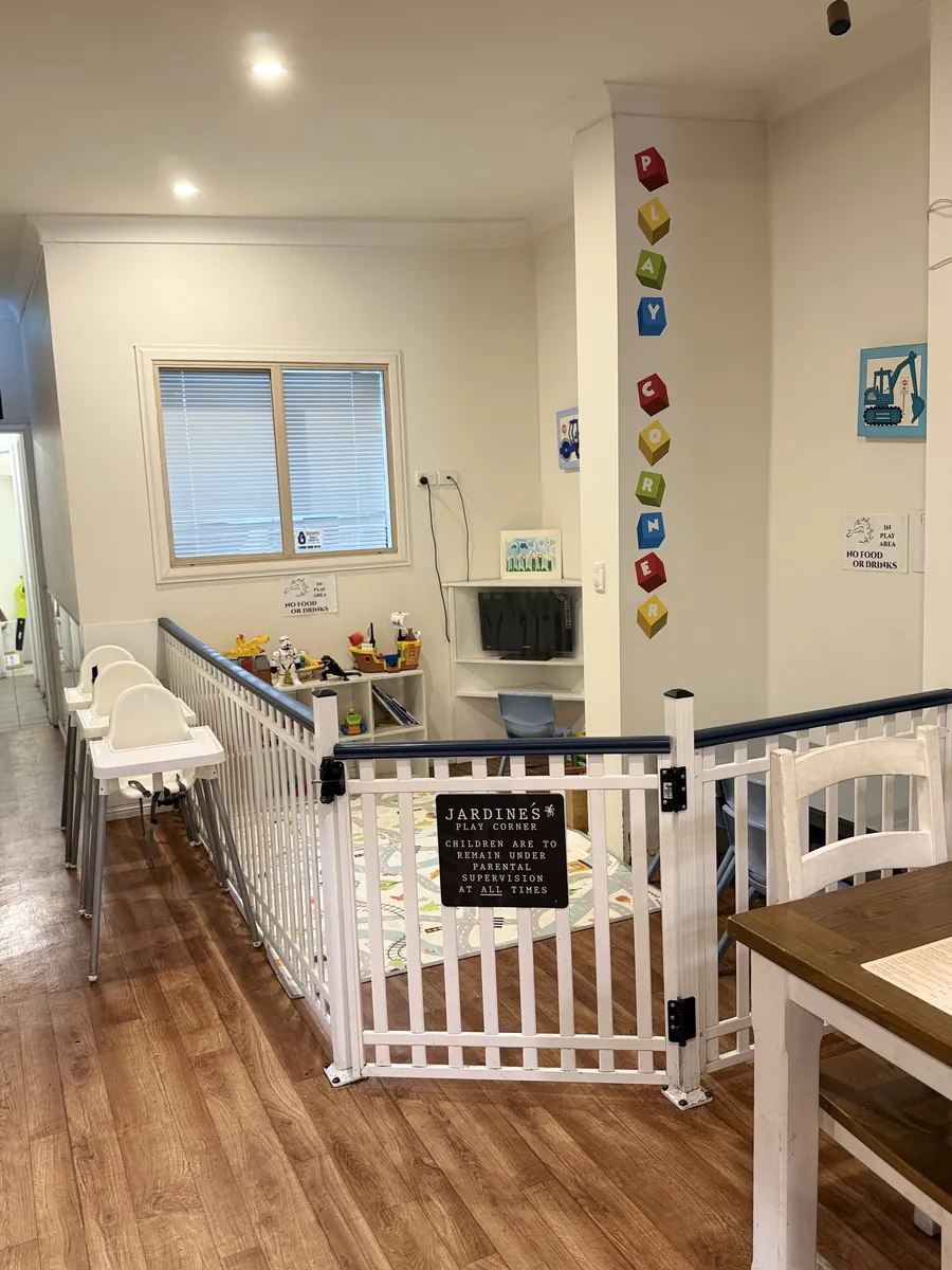 The fenced kids’ play corner with toys, a play mat and high chairs