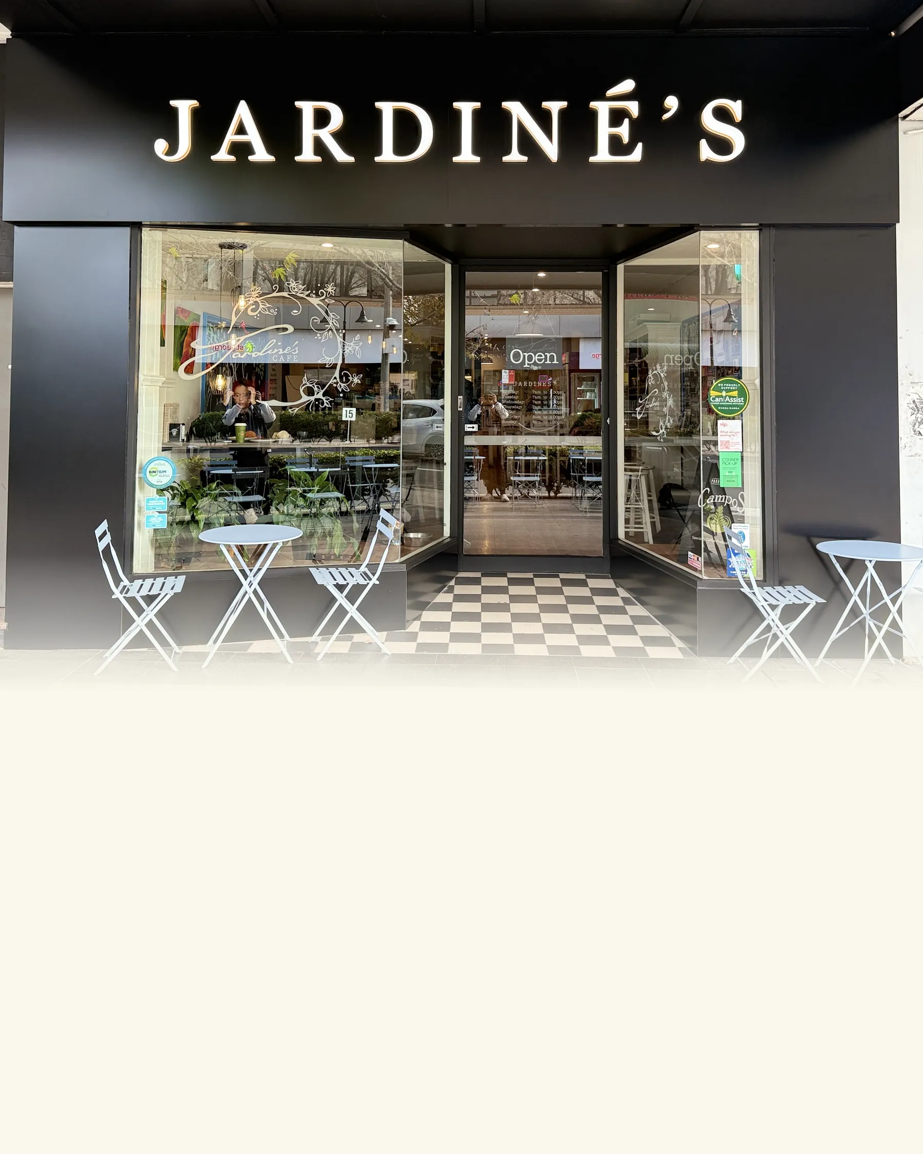 Jardine’s black shopfront on Baylis Street with its lit sign and tables on the footpath